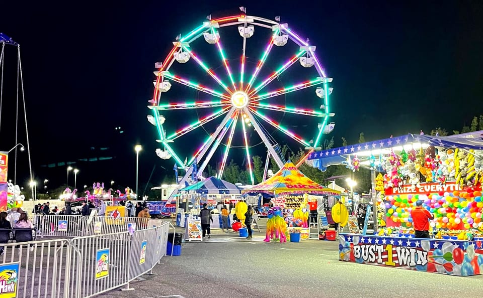 A lit-up ferris wheel on a carnival runway.